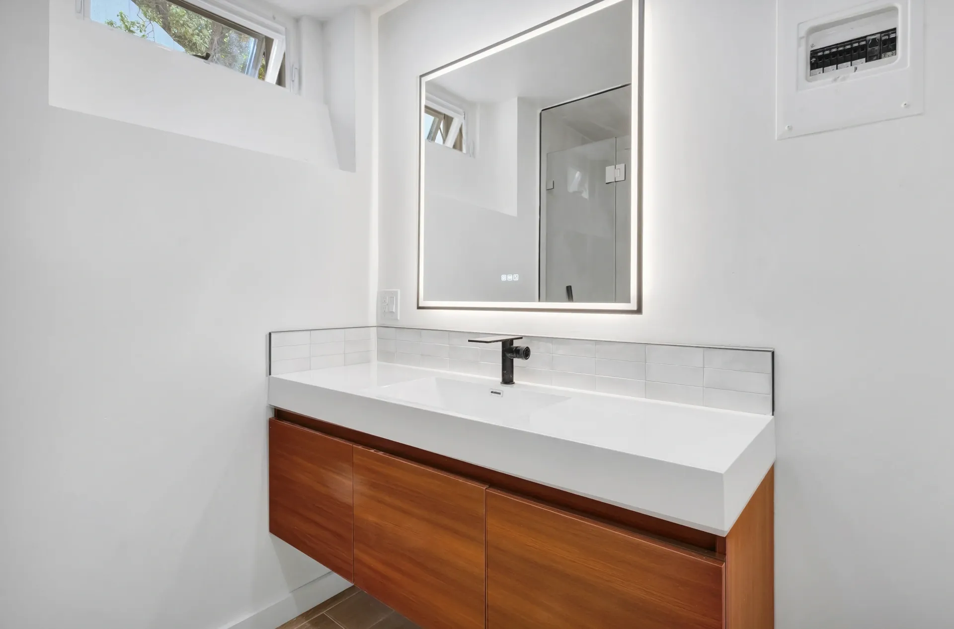 1145 S Longwood Ave Mid-Wilshire — Bathroom: Powder room with floating wood vanity and backlit mirror