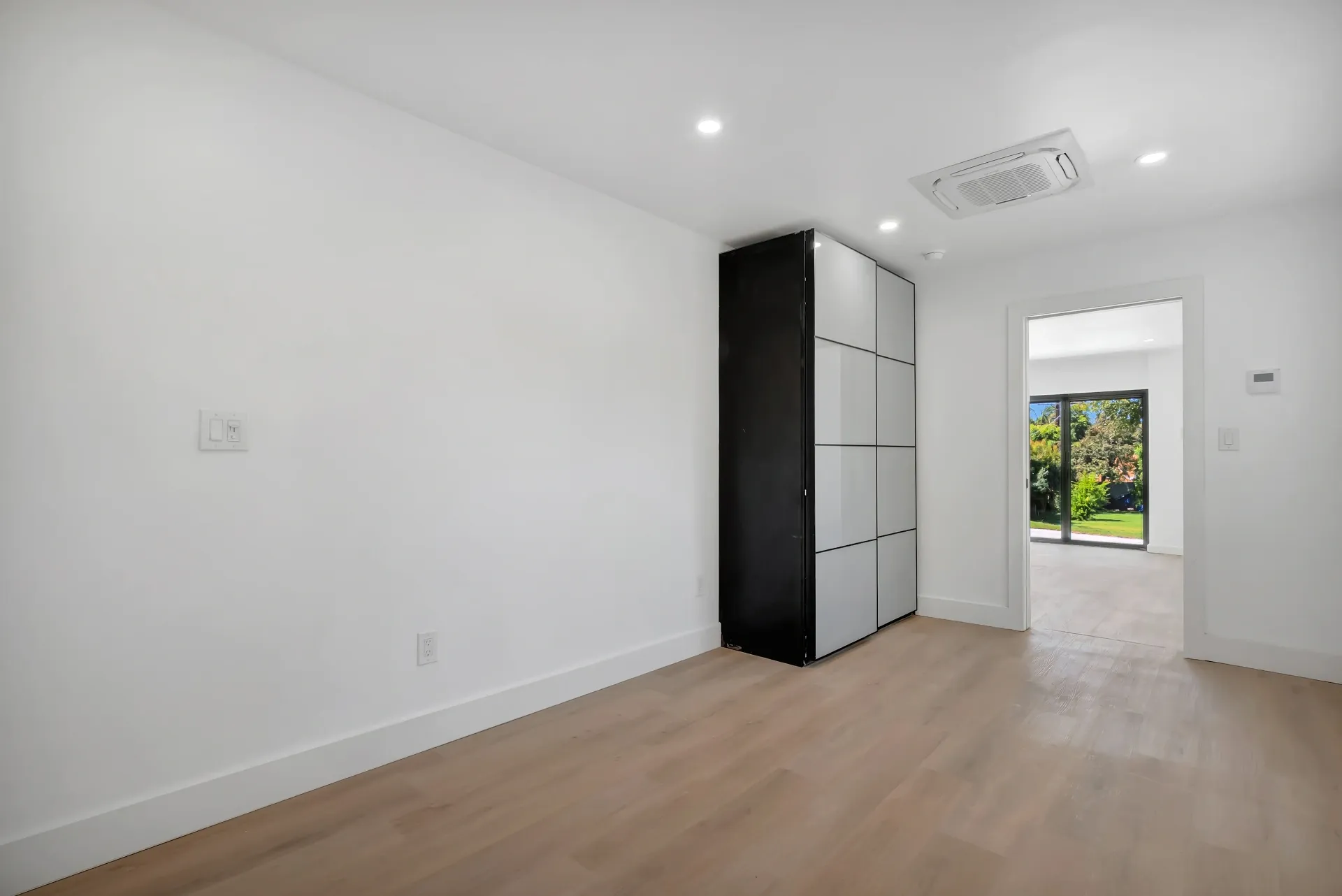 1145 S Longwood Ave Mid-Wilshire — Bedroom: Modern bedroom with black accent storage and garden access
