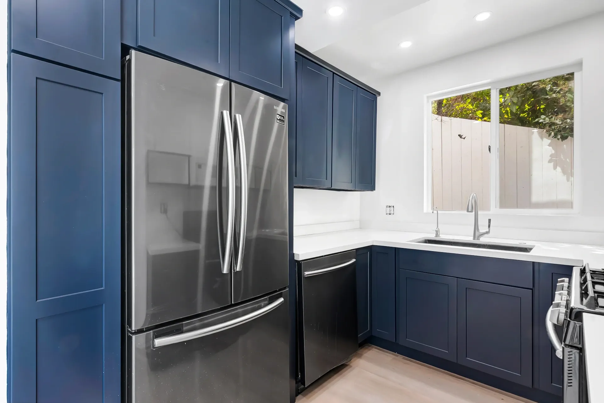 1145 S Longwood Ave Mid-Wilshire — Kitchen: Compact kitchen with navy blue cabinets and stainless steel appliances