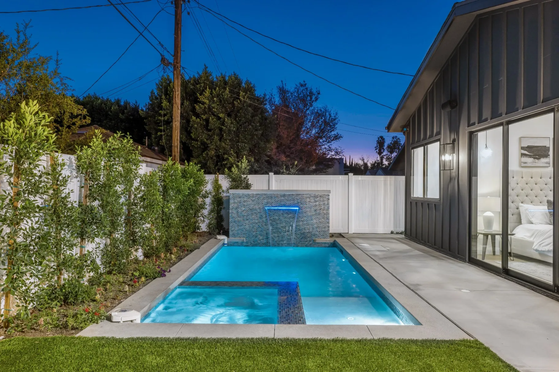 14602 Morrison St — Backyard: Luxury pool and spa with integrated hot tub and blue mosaic tile waterfall feature at twilight