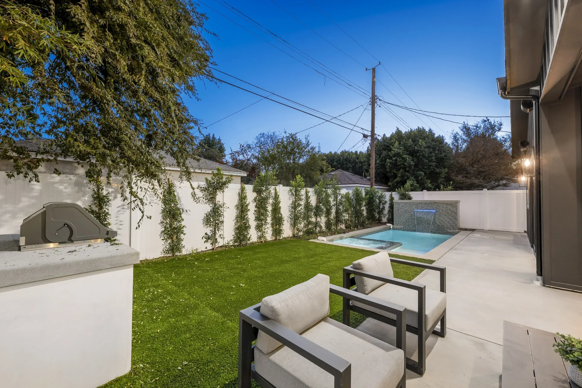 14602 Morrison St — Backyard: Outdoor seating area with modern patio furniture and outdoor kitchen with concrete countertops