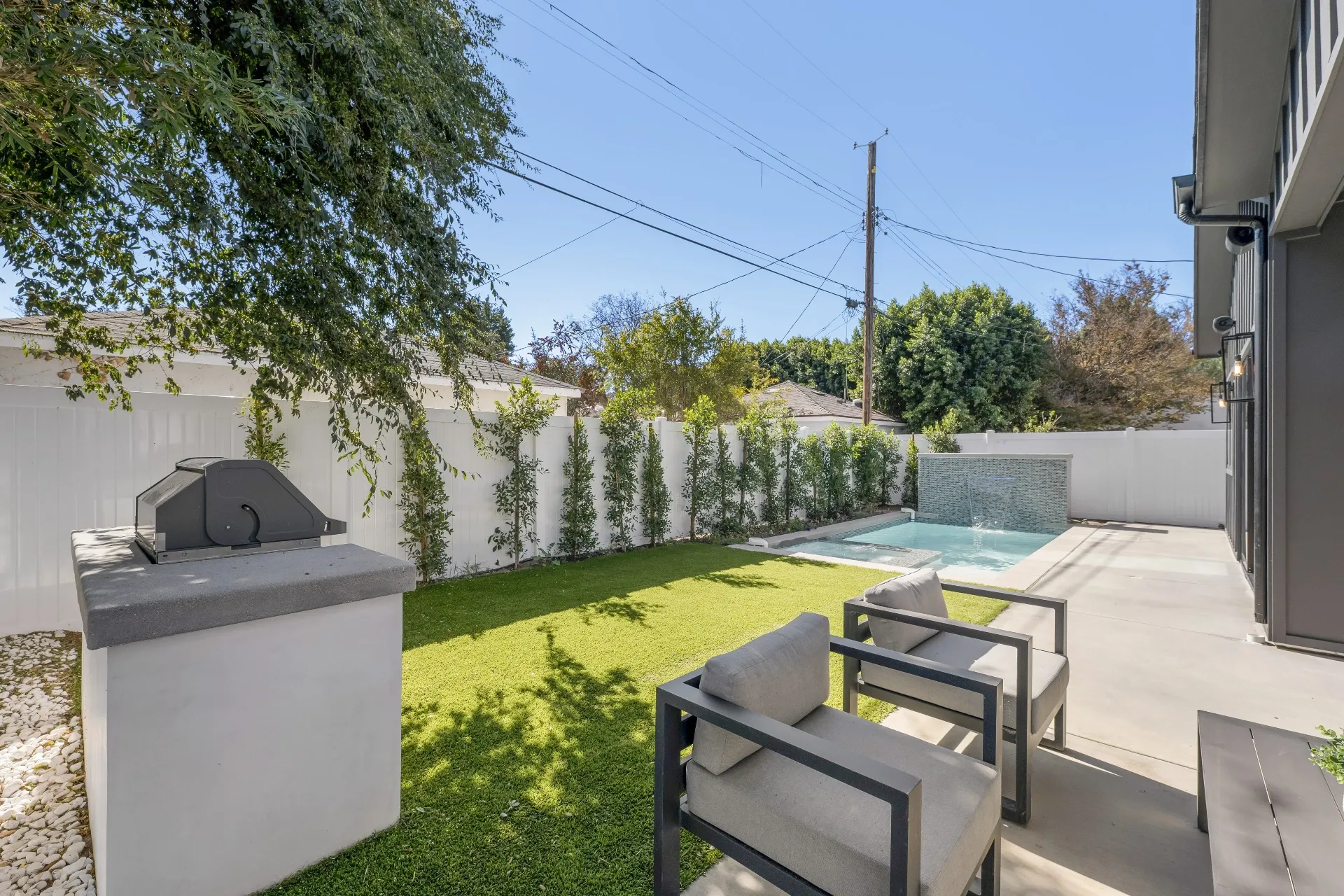 14602 Morrison St — Backyard: Backyard overview with artificial turf lawn, outdoor seating area, and integrated pool design