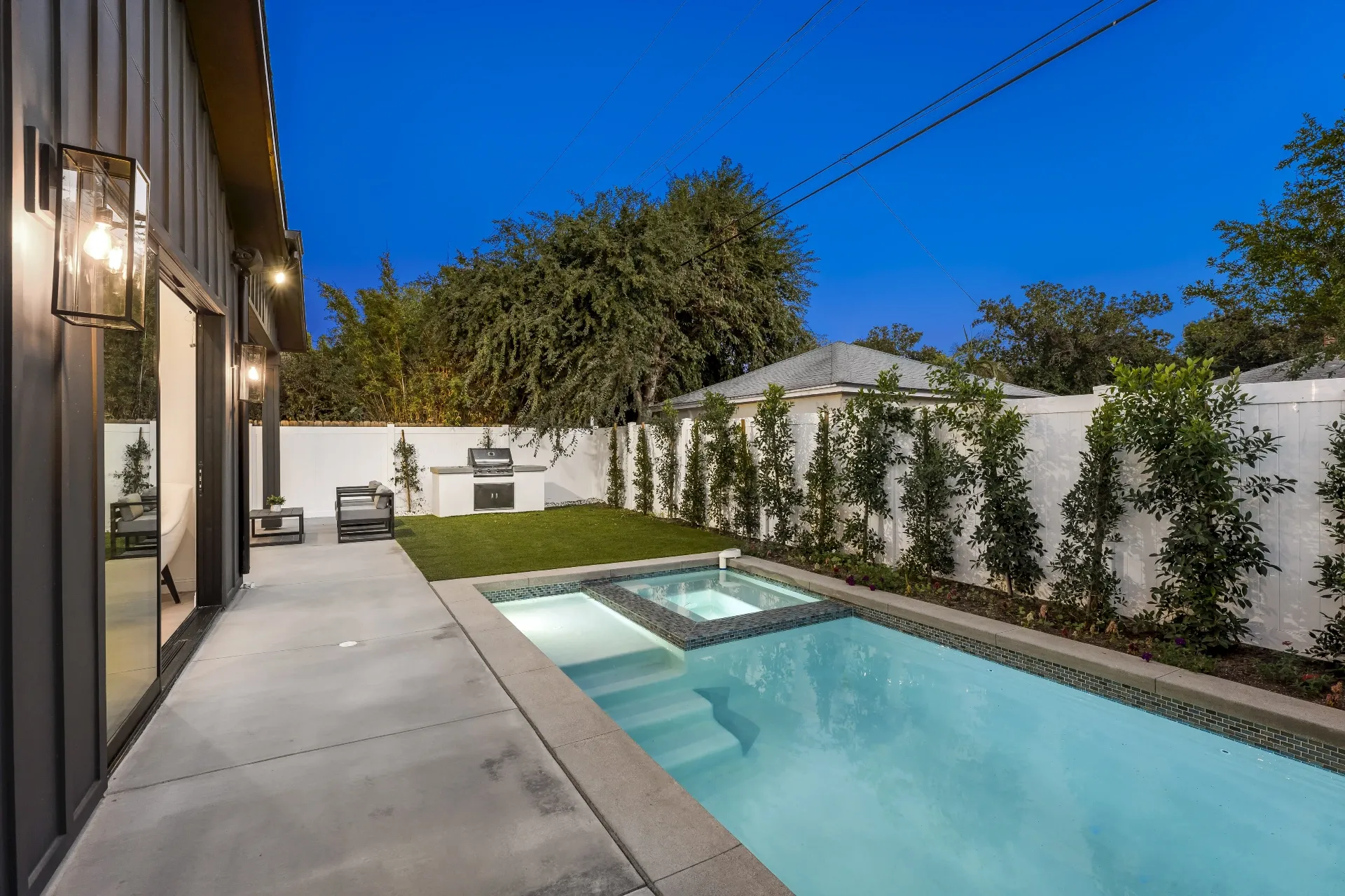14602 Morrison St — Backyard: Twilight backyard view with illuminated pool, spa, and outdoor BBQ area with modern seating