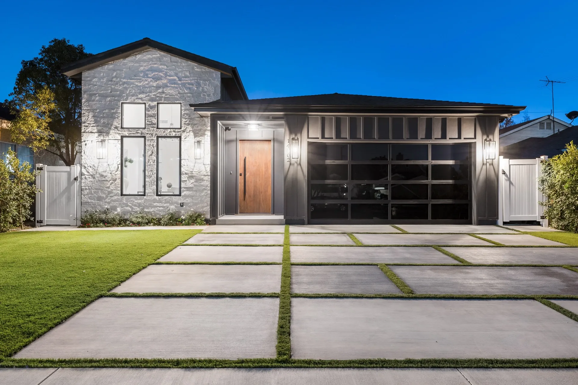 14602 Morrison St — Exterior: Modern farmhouse front elevation with stone wall and glass garage door at twilight