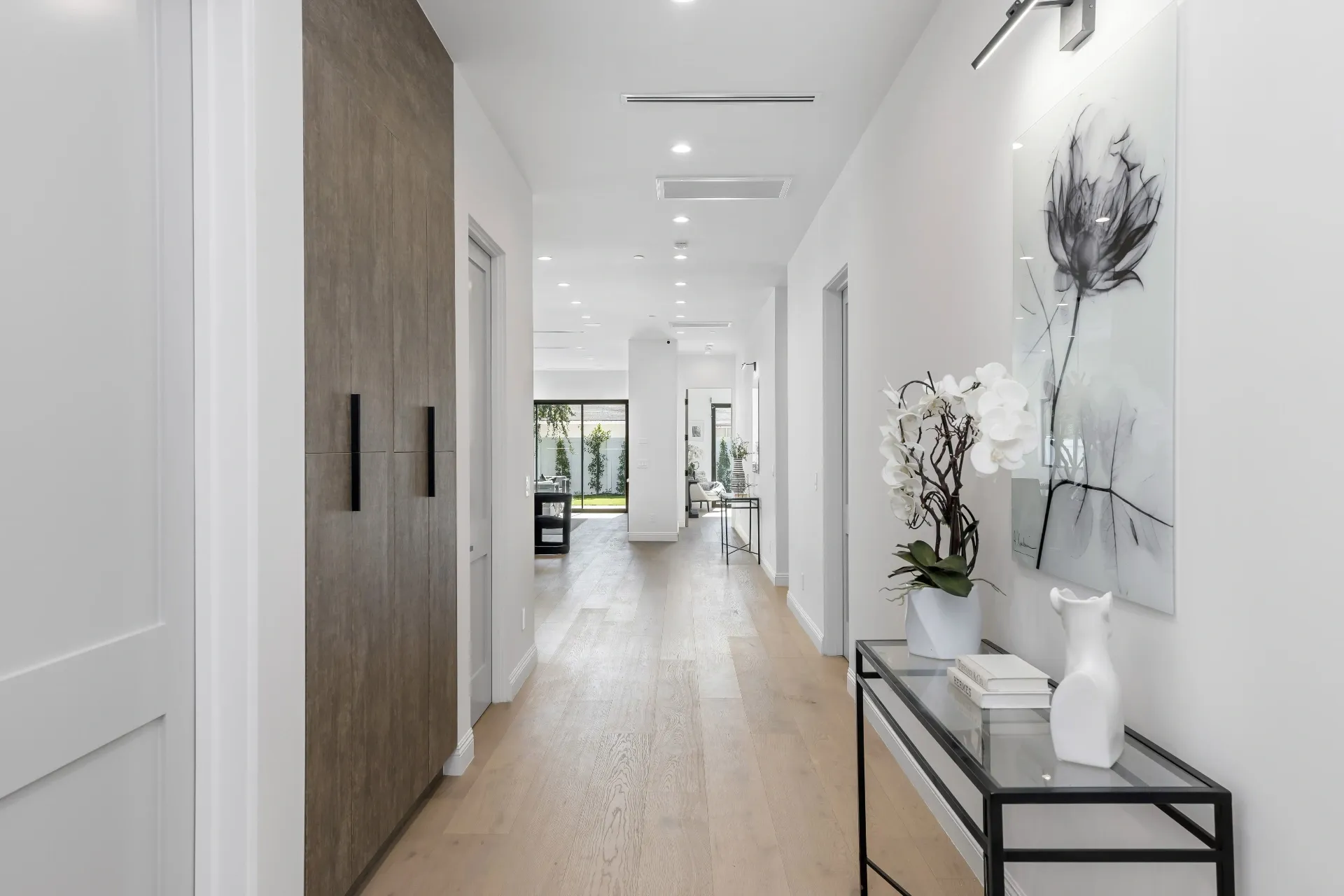 14602 Morrison St — Living Areas: Modern hallway with wood-grain storage and botanical artwork