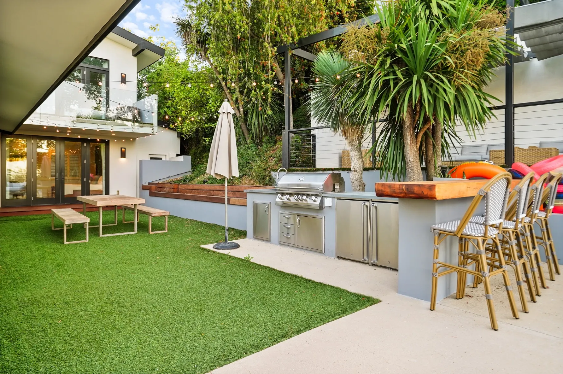 11308 Dona Teresa Dr — Backyard: Outdoor kitchen with stainless steel appliances, bar seating, and artificial grass dining area