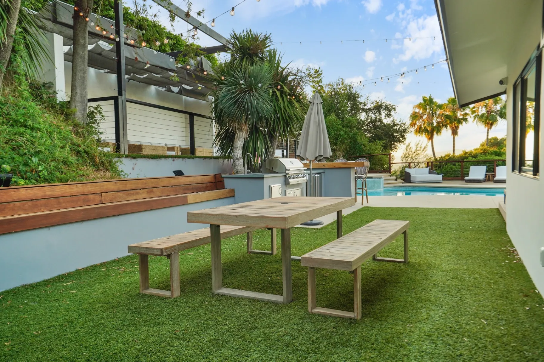 11308 Dona Teresa Dr — Backyard: Outdoor dining area with teak furniture, BBQ grill, and hillside landscaping