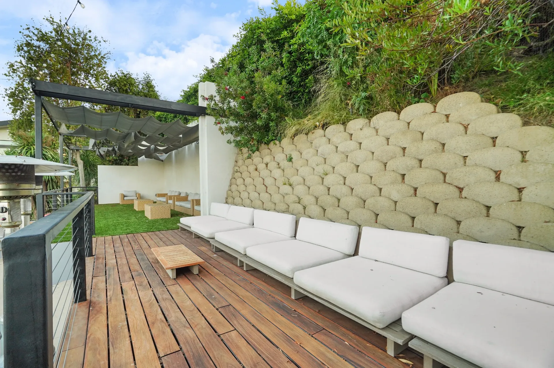 11308 Dona Teresa Dr — Backyard: Outdoor seating area with modern sectional and decorative retaining wall backdrop