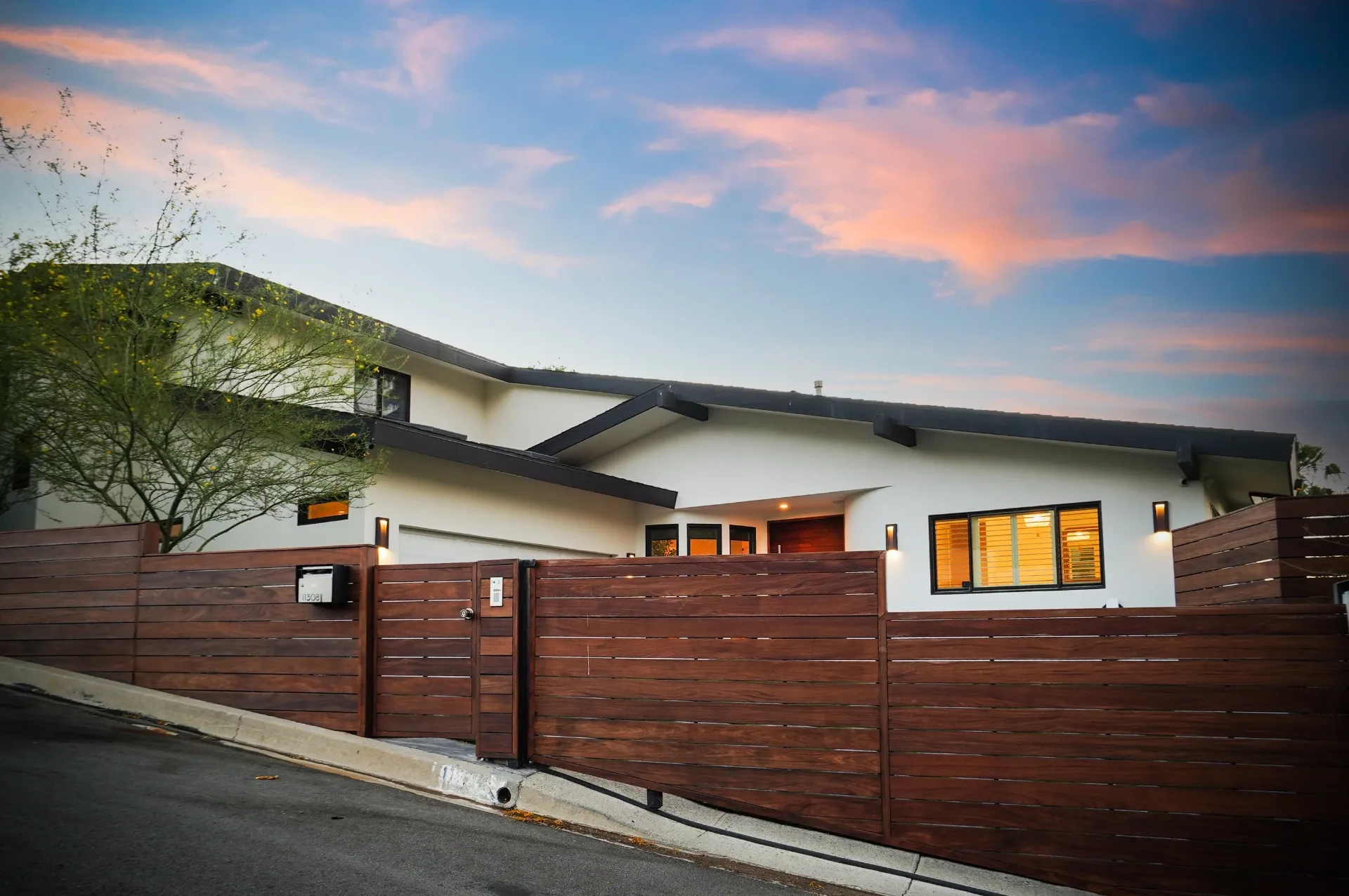 11308 Dona Teresa Dr — Exterior: Sunset street view with dramatic sky and warm interior lighting through horizontal wood fence