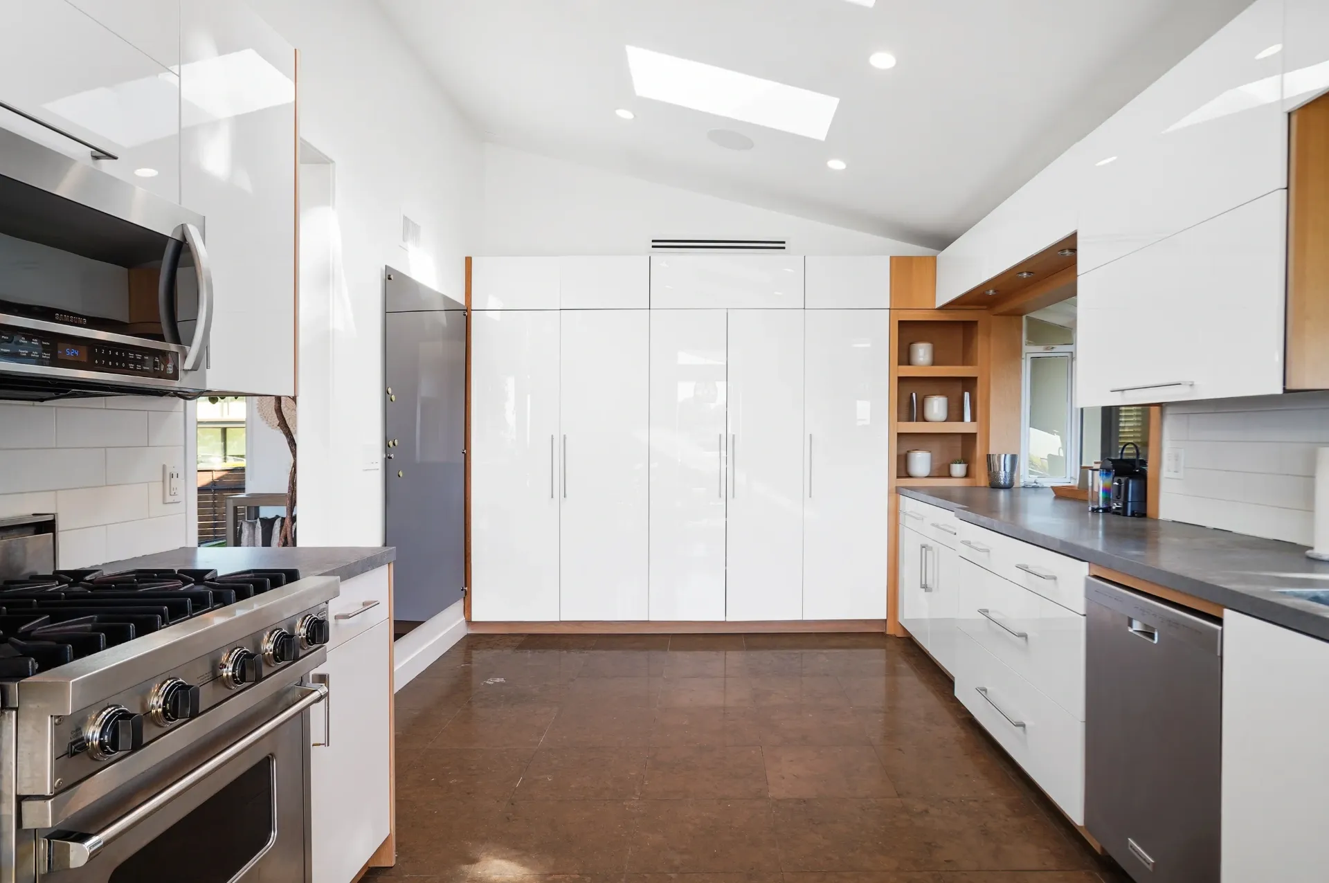 11308 Dona Teresa Dr — Kitchen: Galley kitchen with skylights, white cabinets, and wood trim throughout