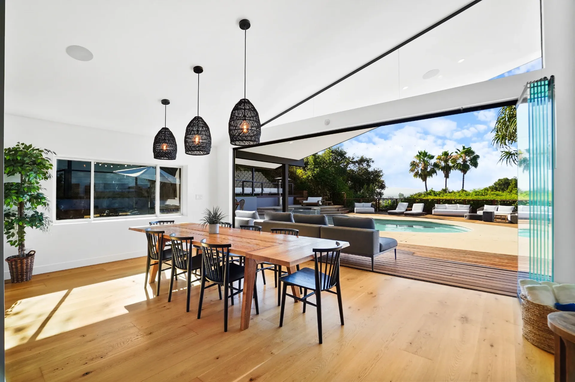 11308 Dona Teresa Dr — Kitchen: Open dining area with wood table, woven pendant lights, and seamless pool views