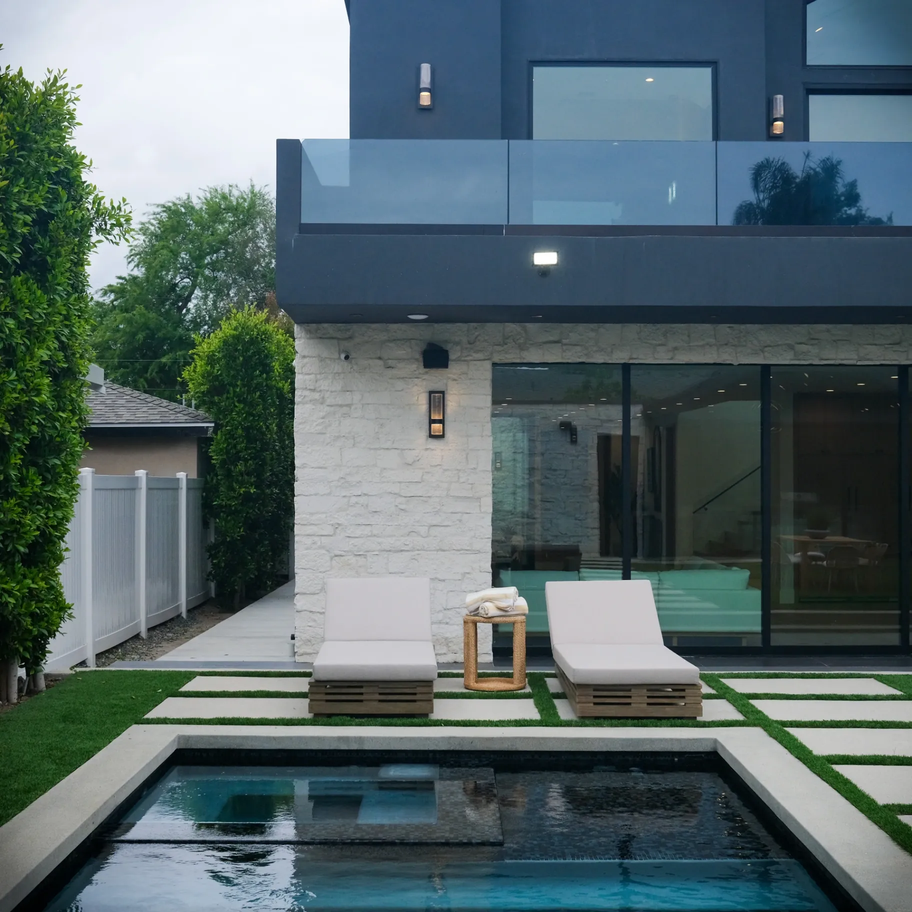 15602 Morrison St — Backyard: 15602 Morrison St — Pool area with modern lounge chairs, artificial grass, and contemporary home architecture