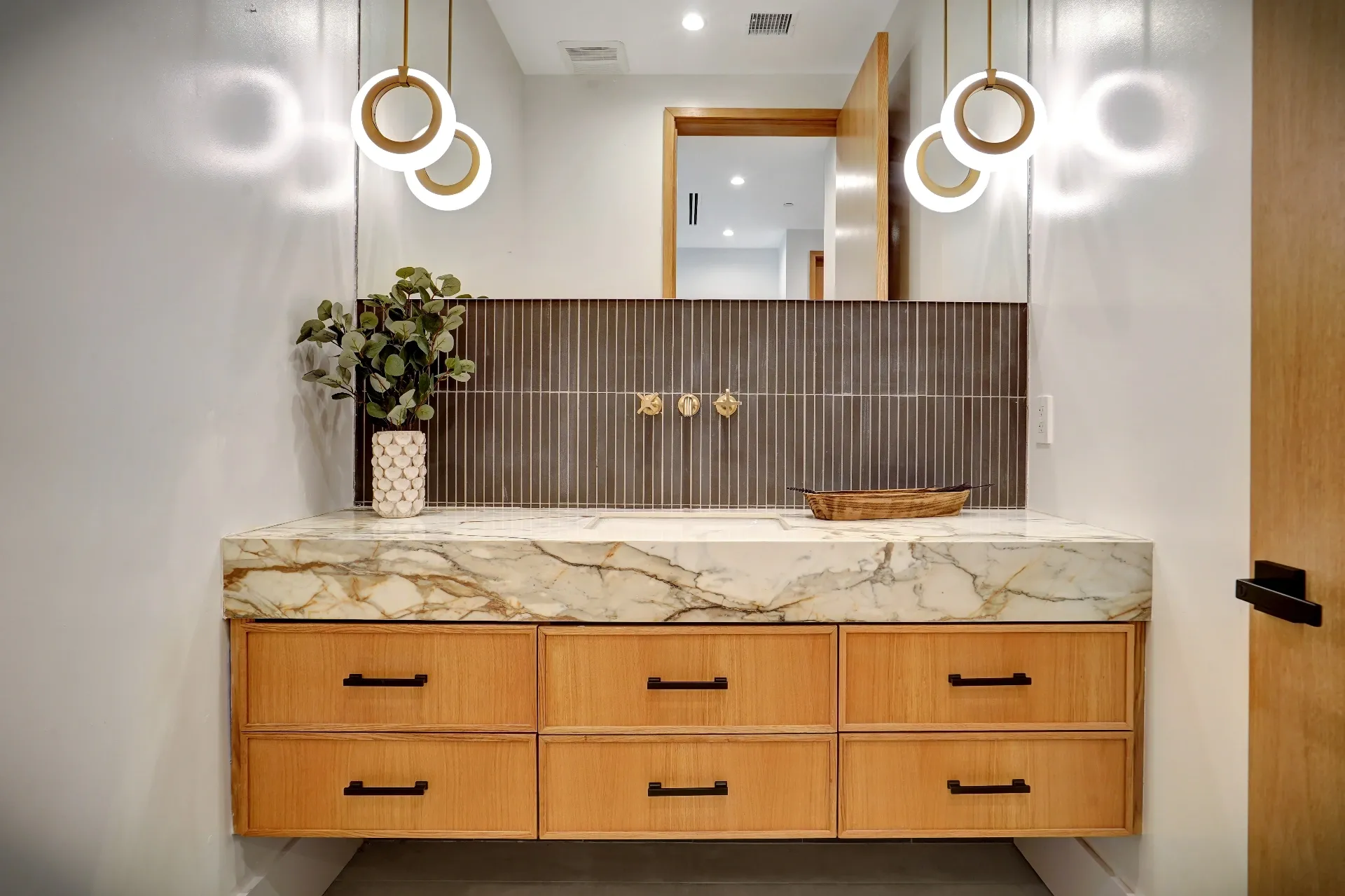 15602 Morrison St — Bathrooms: 15602 Morrison St — Contemporary bathroom vanity with wood cabinetry, marble waterfall countertop, fluted tile backsplash, and brass fixtures