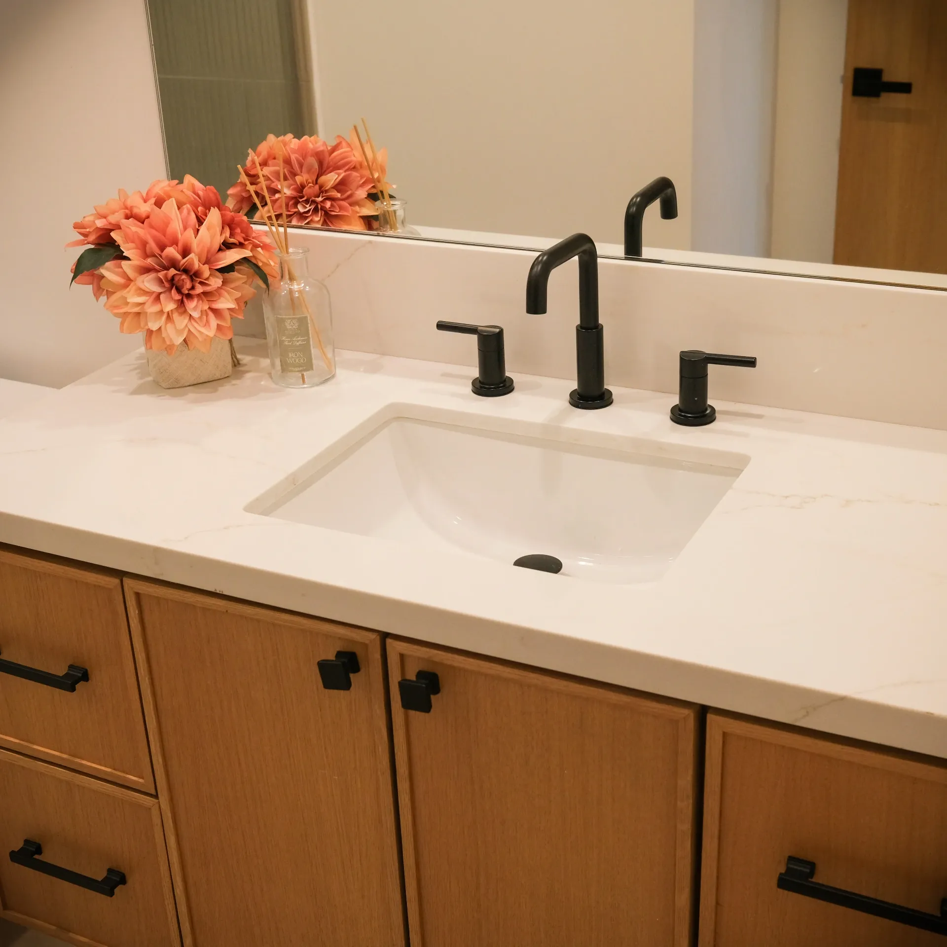 15602 Morrison St — Bathrooms: 15602 Morrison St — Bathroom vanity with wood cabinetry, white marble countertop, black fixtures, and fresh floral styling