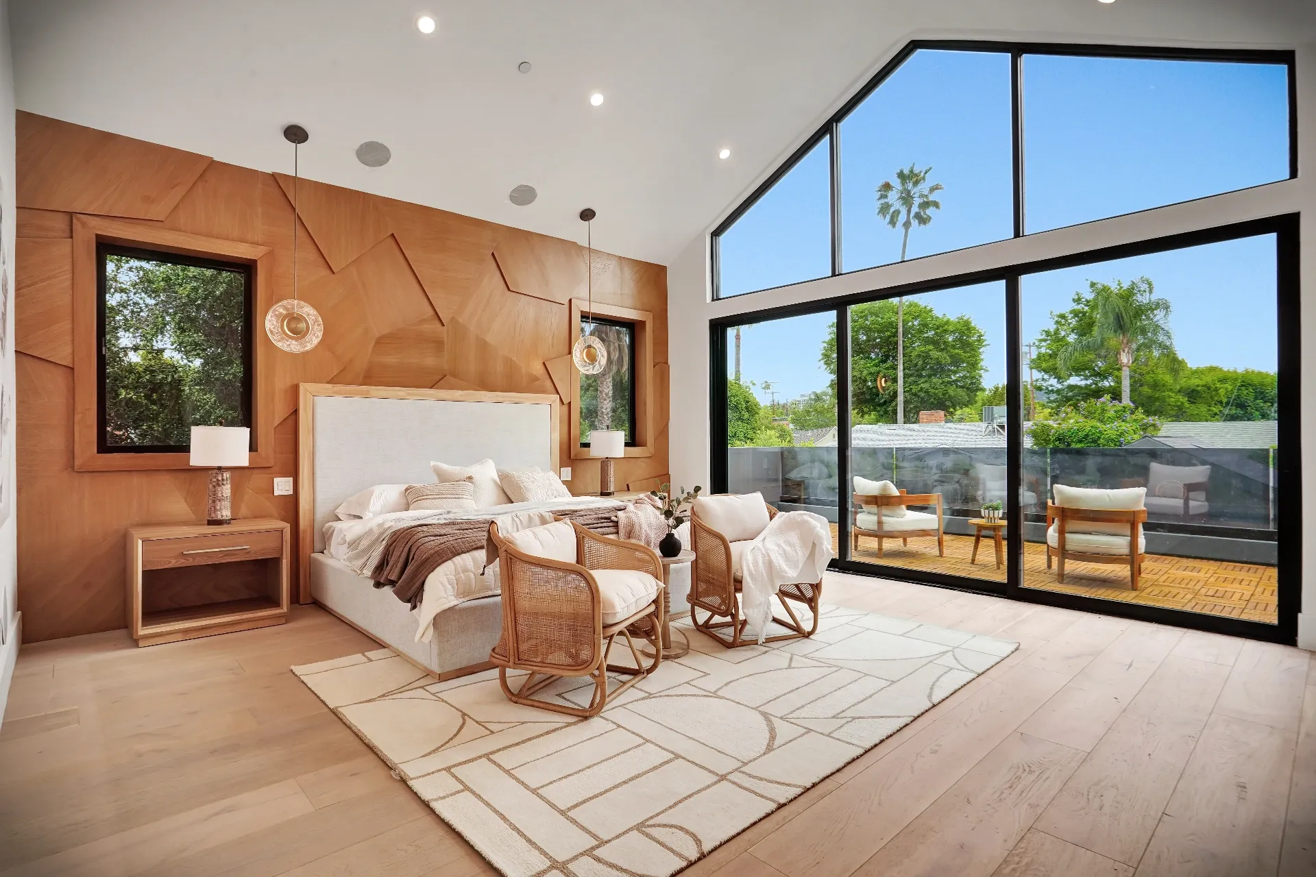 15602 Morrison St — Bedrooms: 15602 Morrison St — Primary bedroom with geometric wood accent wall, neutral bedding, rattan chairs, and floor-to-ceiling windows