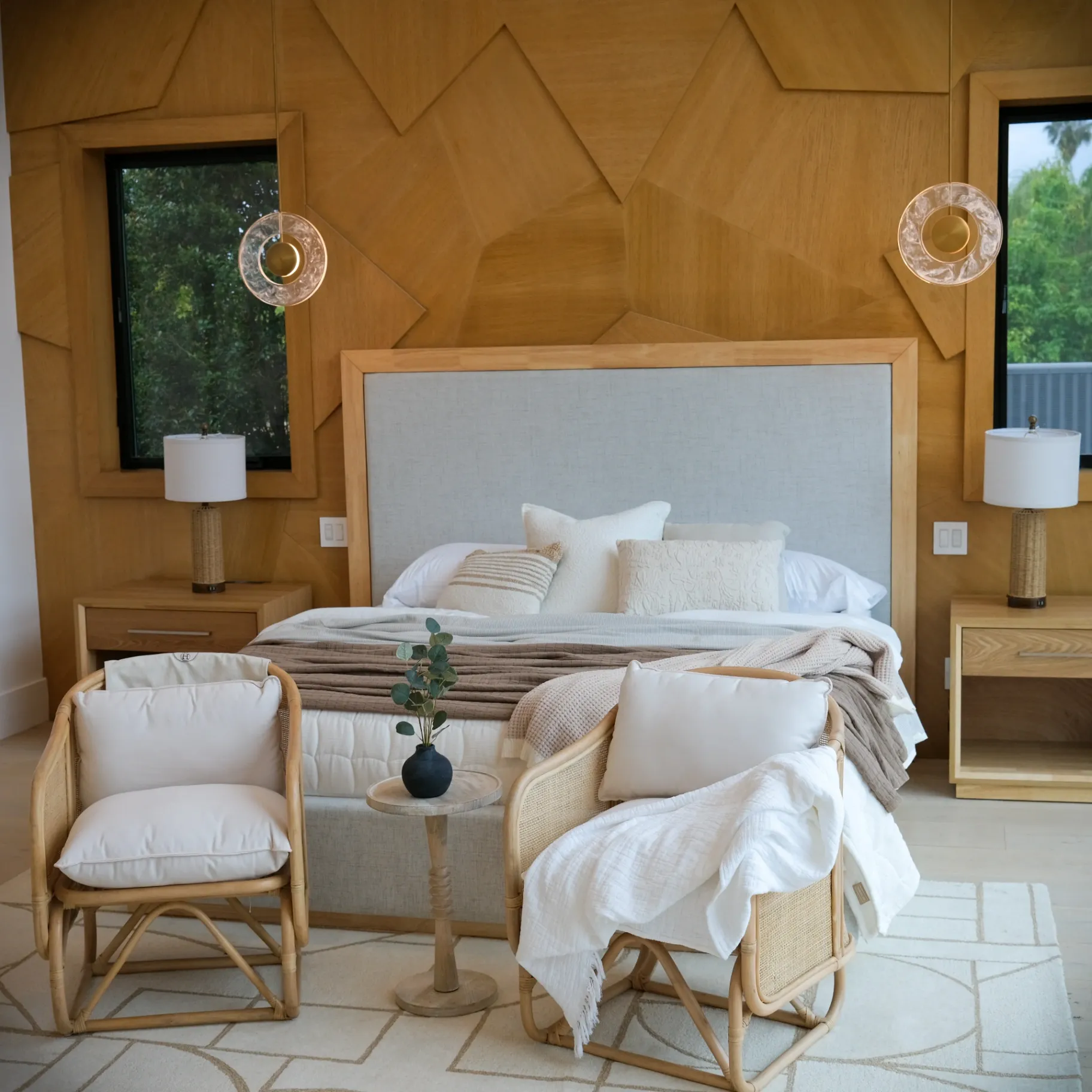 15602 Morrison St — Bedrooms: 15602 Morrison St — Primary suite with geometric wood accent wall, upholstered headboard, rattan seating area, and ensuite bathroom access