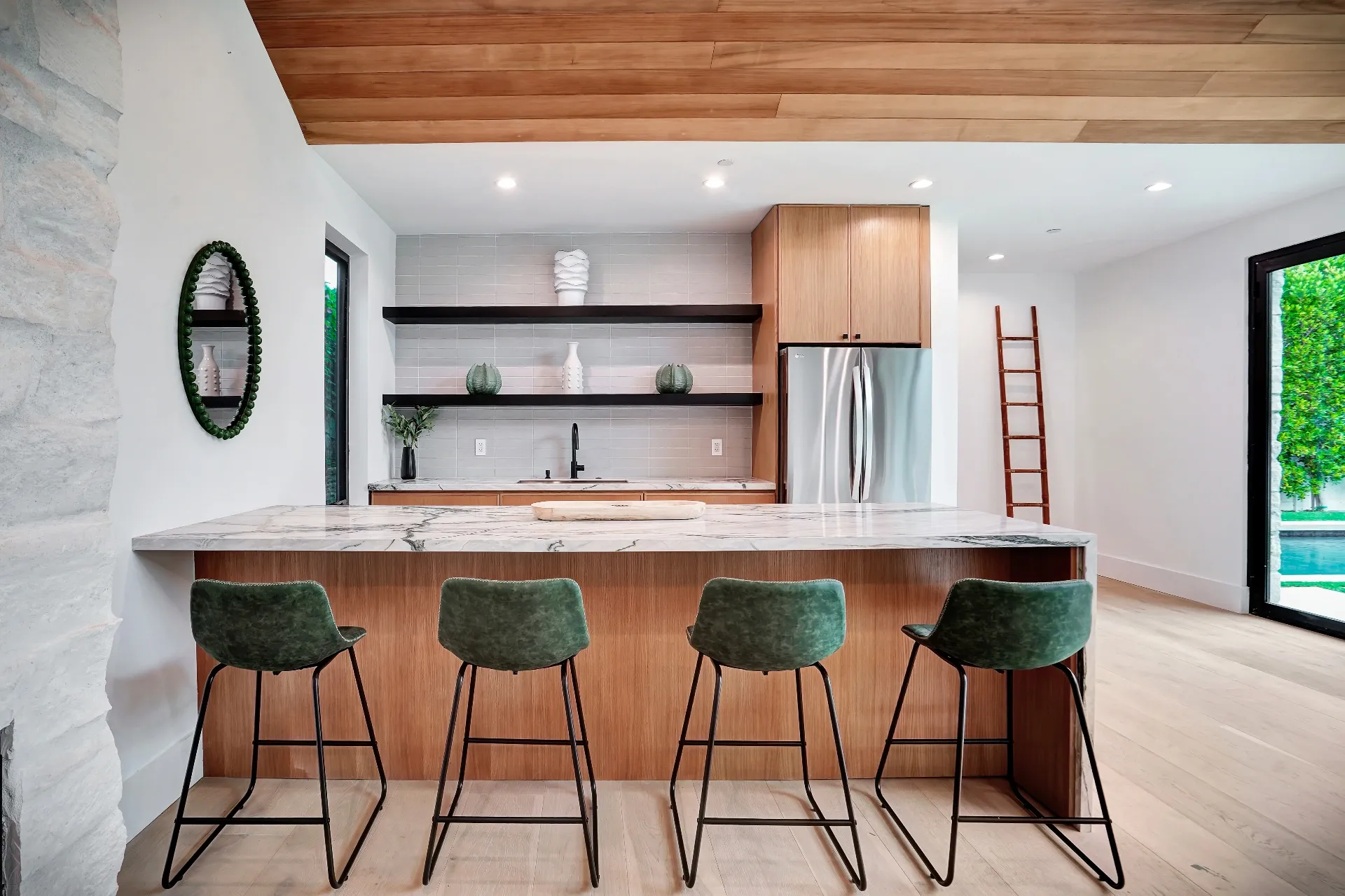 15602 Morrison St — Guest House: 15602 Morrison St — Guest house kitchen island with four green bar stools, marble countertops, and wood cabinetry