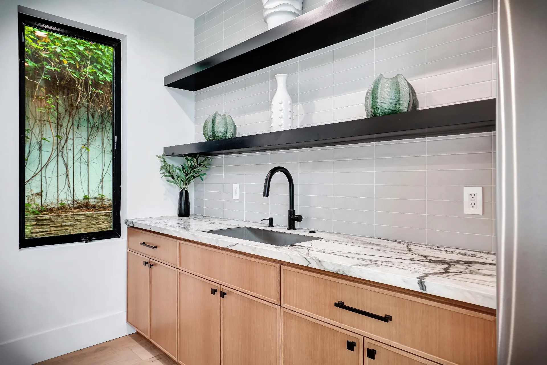 15602 Morrison St — Guest House: 15602 Morrison St — Guest house kitchen with floating black shelves, marble countertops, and modern fixtures