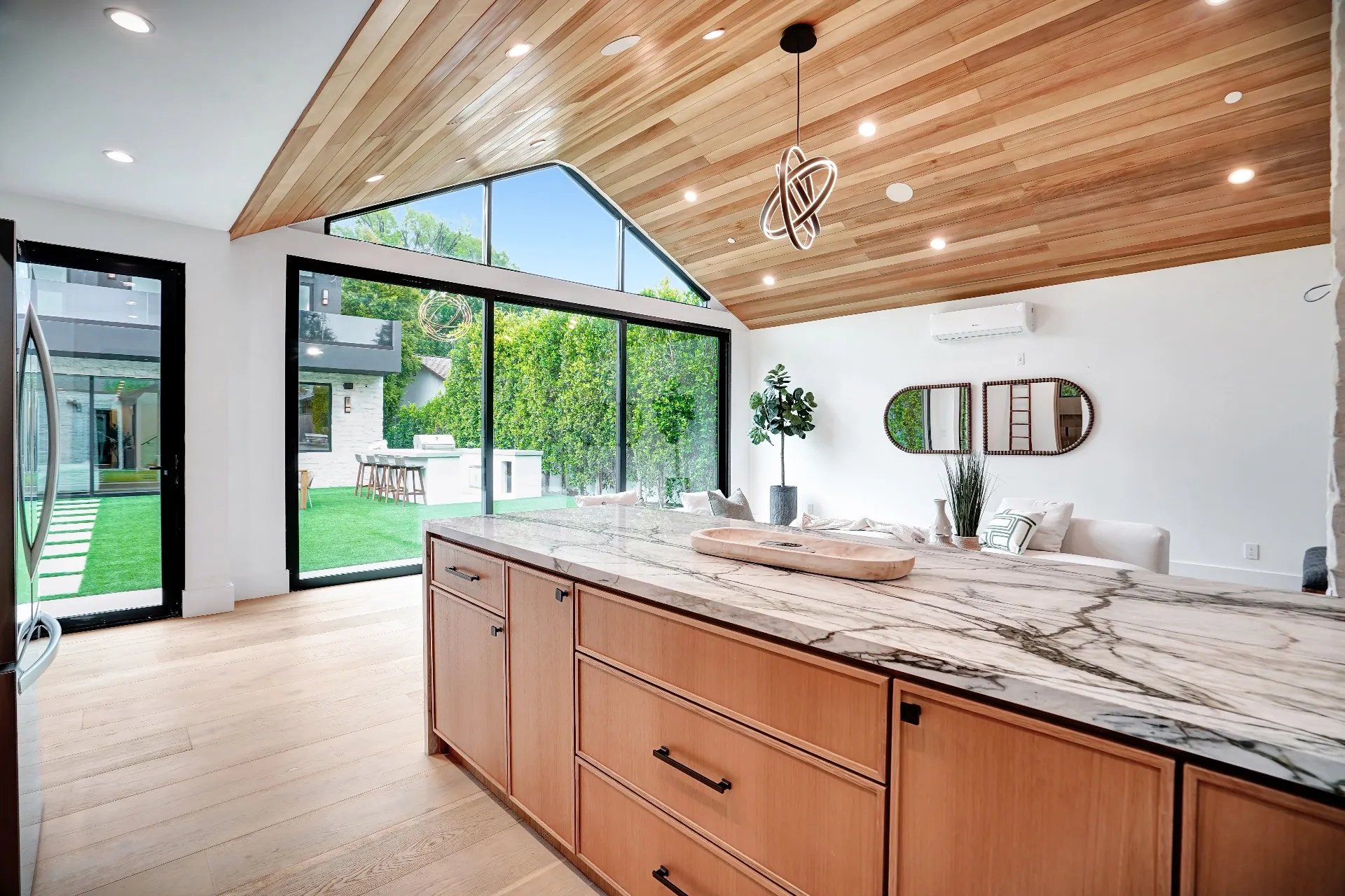 15602 Morrison St — Guest House: 15602 Morrison St — Guest house kitchen with vaulted wood ceiling, marble island, black pendant lighting, and seamless indoor-outdoor views