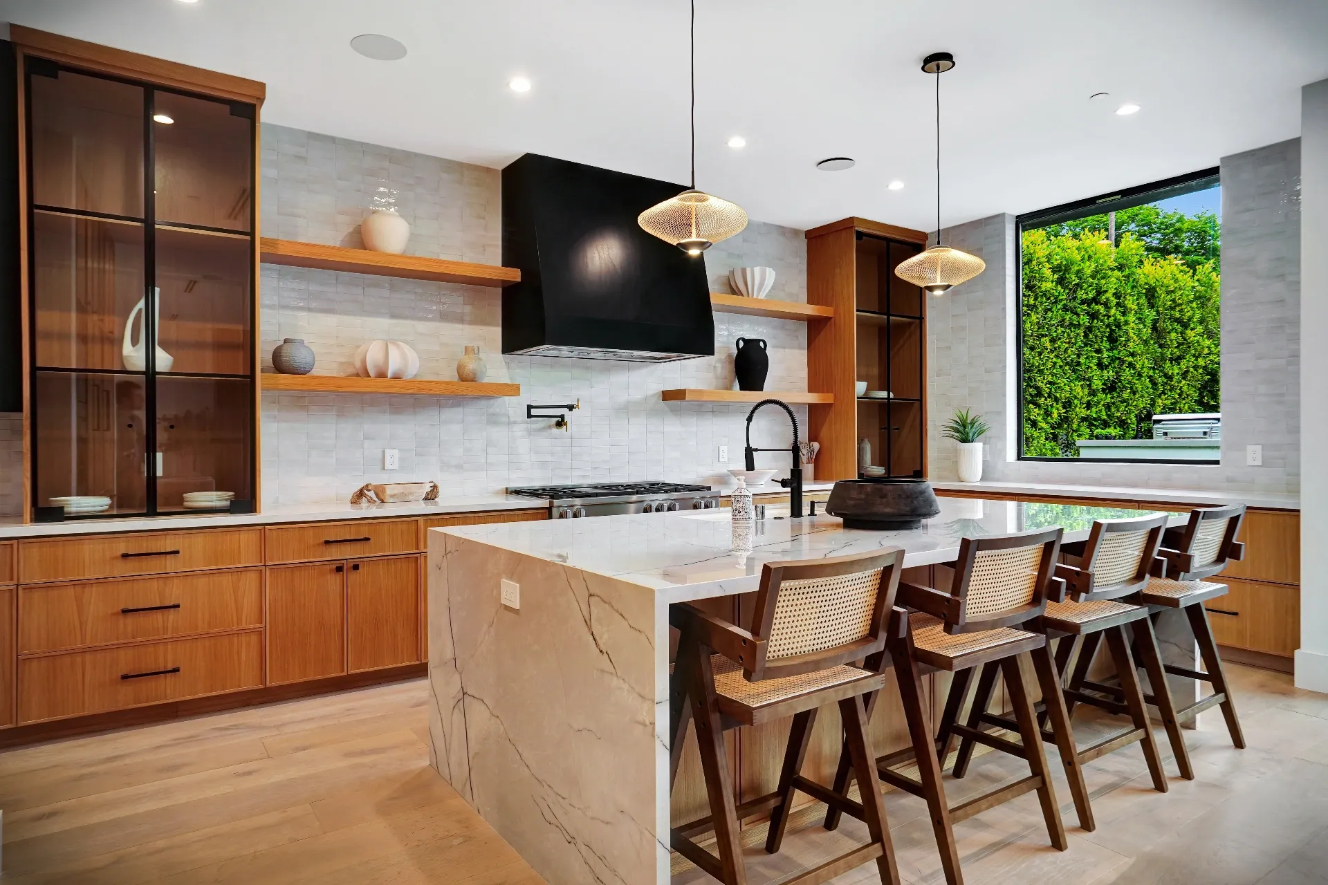 15602 Morrison St — Kitchen: 15602 Morrison St — Kitchen island with marble countertops, wood cabinetry, cane bar seating, and black range hood