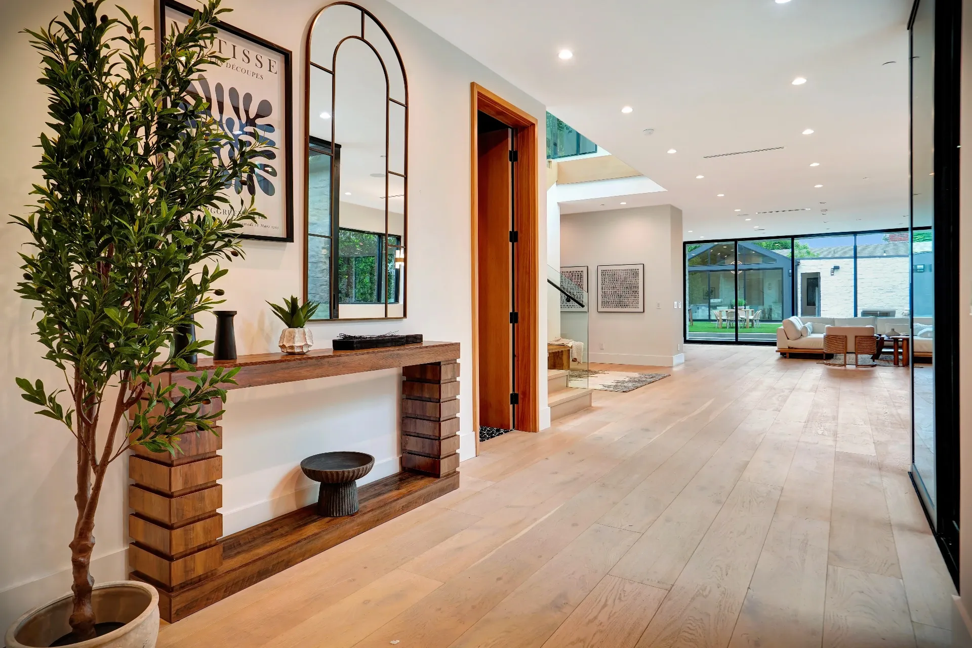 15602 Morrison St — Living Areas: 15602 Morrison St — Entry foyer with built-in wood fireplace, modern console, arched mirror, and seamless living area views
