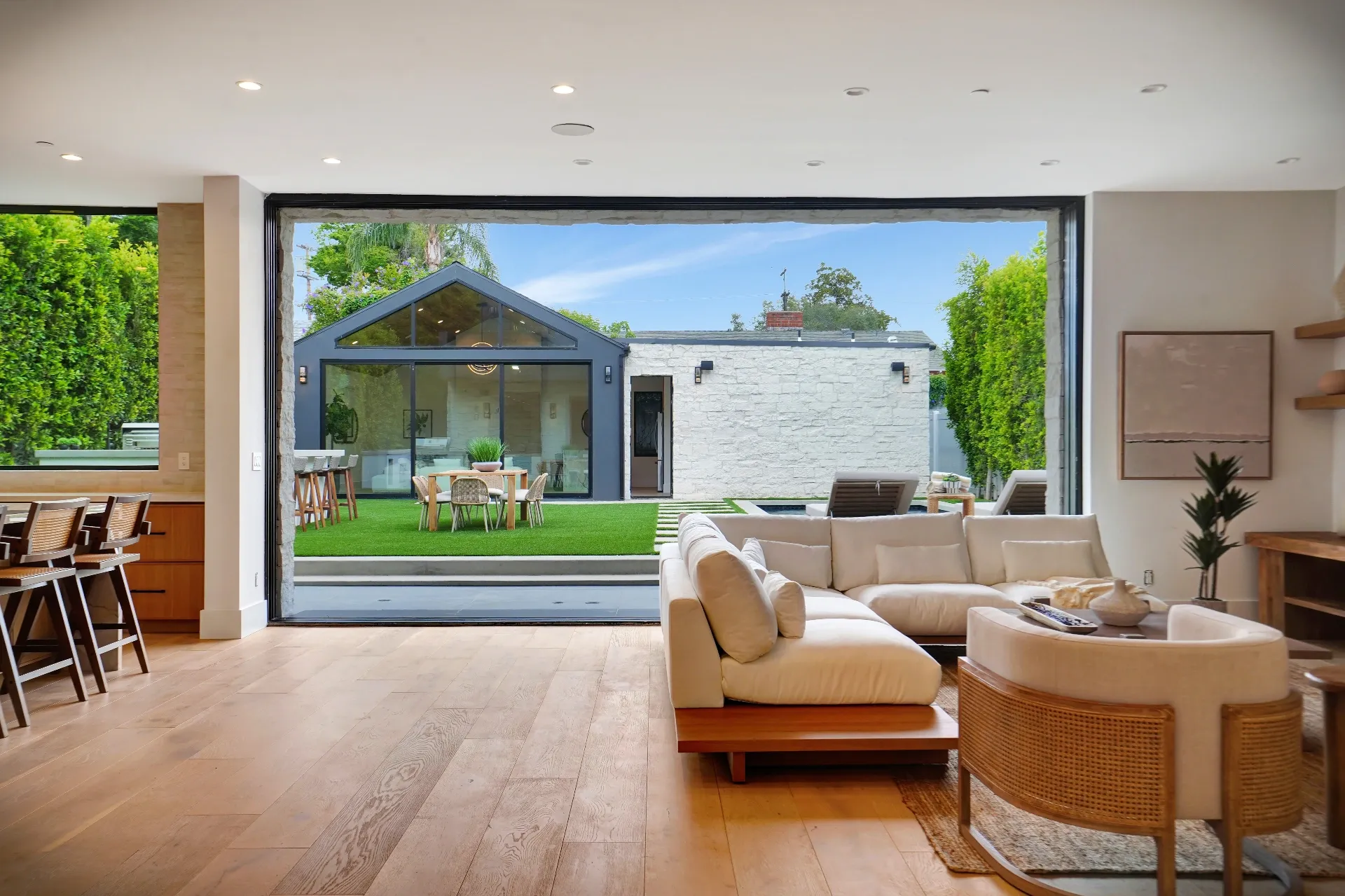 15602 Morrison St — Living Areas: 15602 Morrison St — Living area with white sectional sofa, cane accent chairs, and panoramic sliding doors to outdoor space