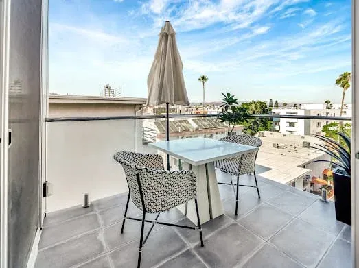 124 S Croft Ave — Exterior: Rooftop terrace dining area with modern table, umbrella, and city views